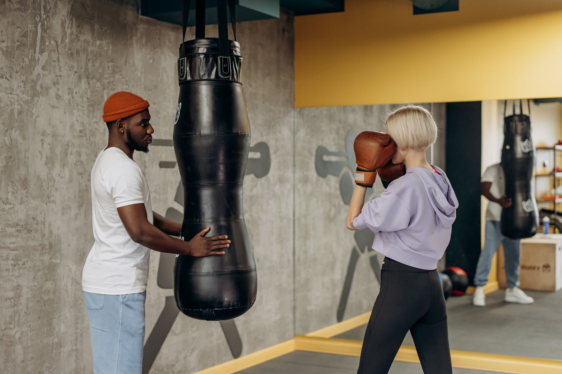 A woman practicing boxing with a coach in an indoor gym setting, focused on a training session.